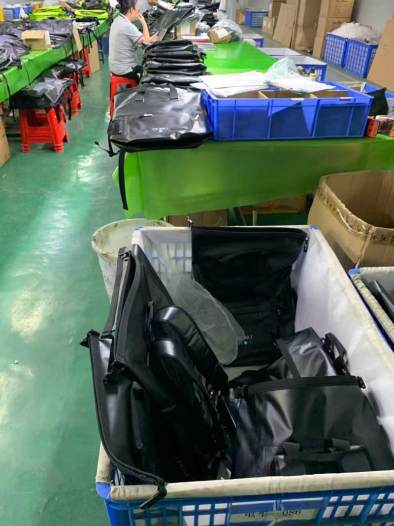 Finished bags in a cloth-lined bin with protective sleeves on zipper pulls and wrapped hardware